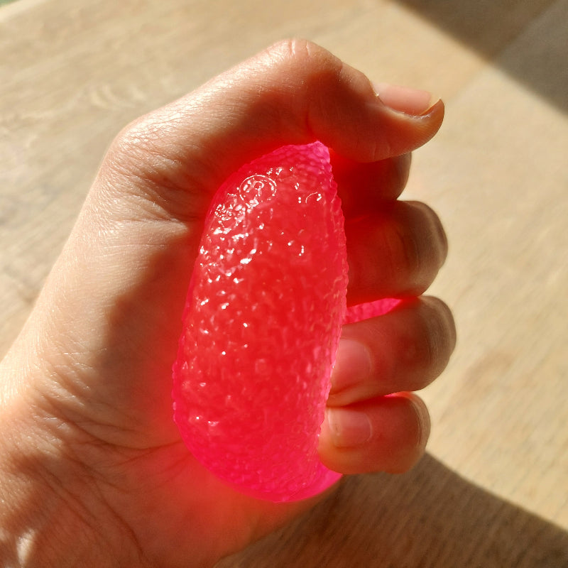 roze gum drop fidget bal van needoh gedrukt in hand, ribbel structuur, sensorisch