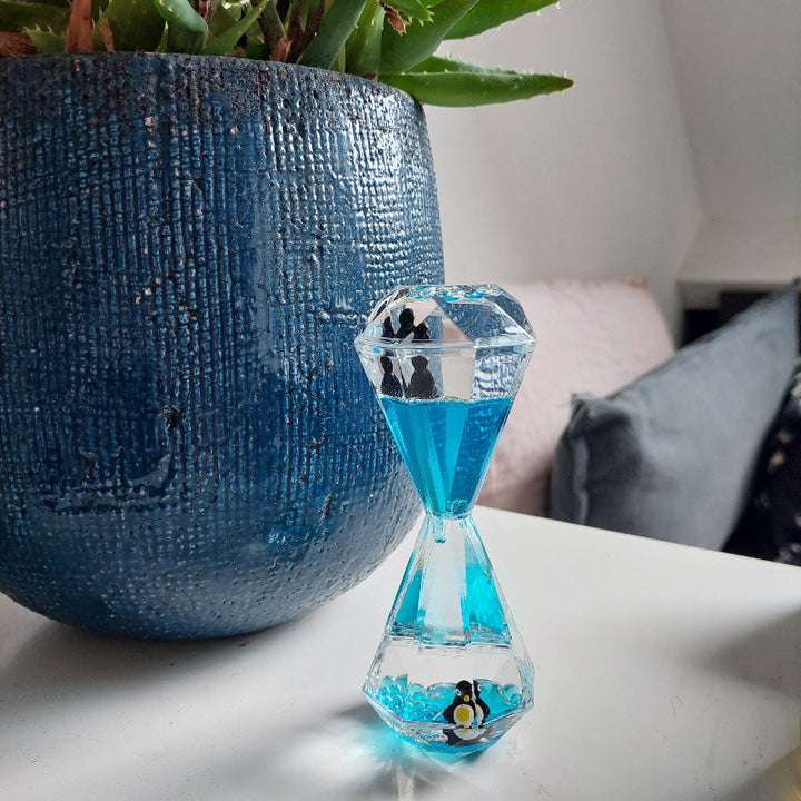 liquid timer, lavaloper, olieloper, zandloper blauw met pinguin op nachtkastje met blauwe plantenpot, sensoriek materiaal