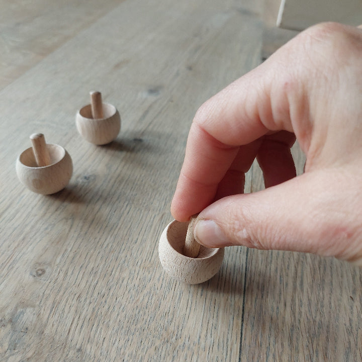 onhandeld hout tol, met hand, drei stuks op tafel, Toys42hands