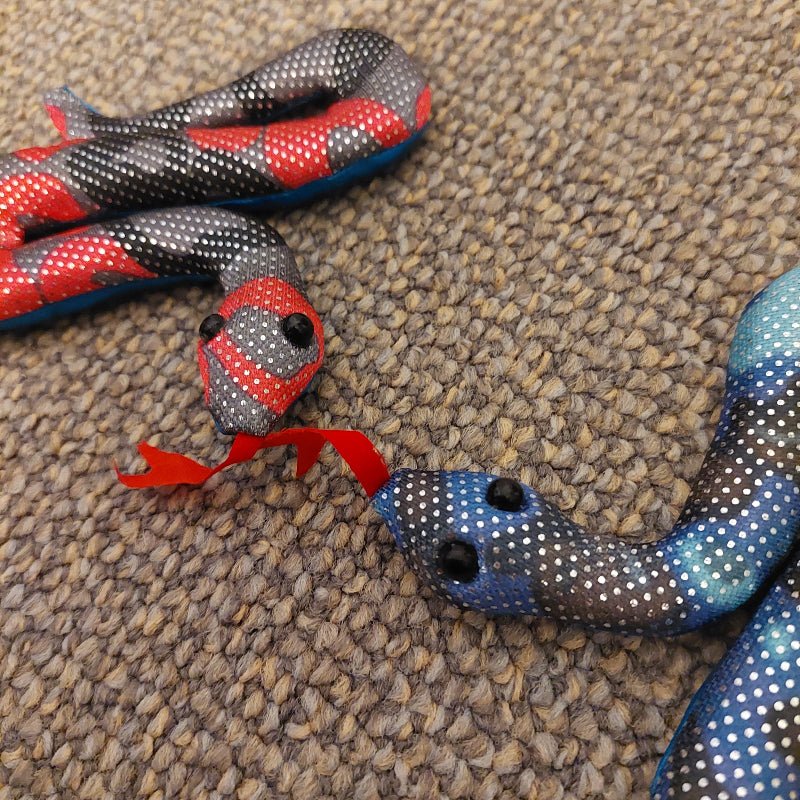 twee mini zanddier slangen in rood en blauw op de grond, sensoriek speelgoed