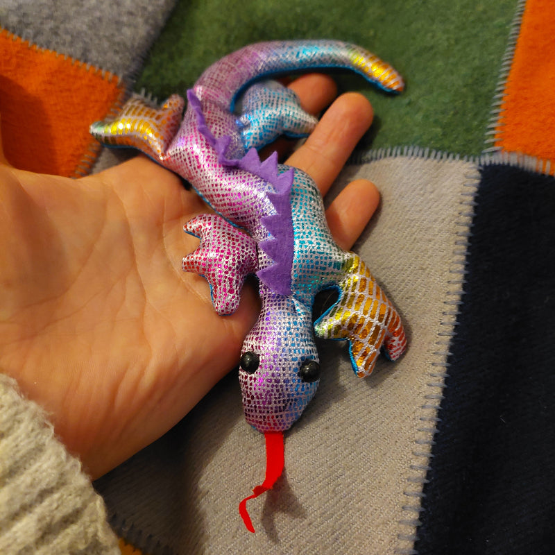 Mini zanddier in regenbogen kleuren in hand op quilt. sensoriekateriaal