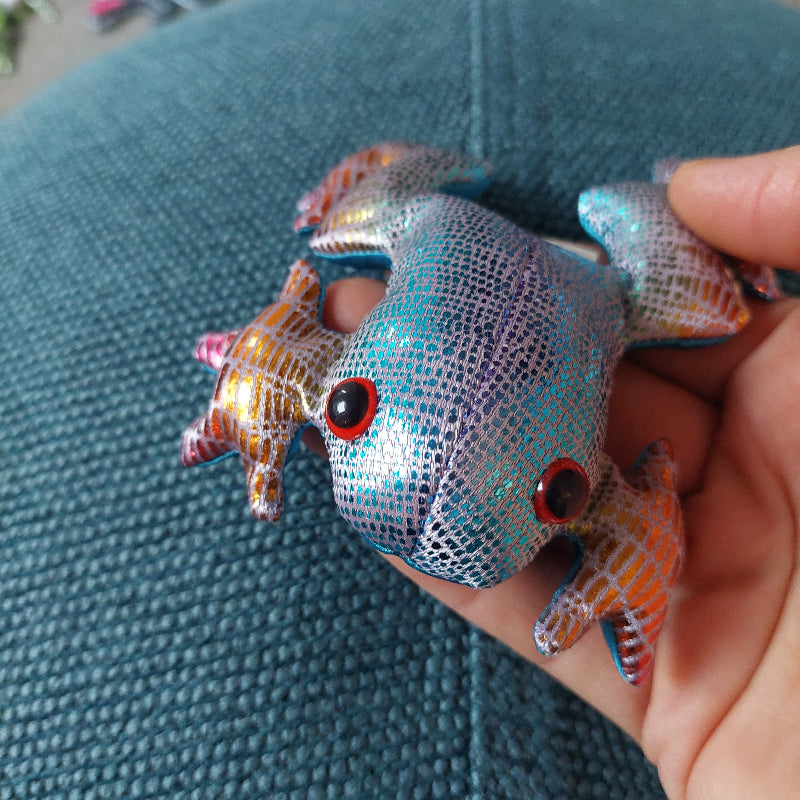 regenboog zanddier kikker op hand voor blauw achtergrond, lichtblauwe kikker met roze poten, goud op de poten, sensoriek materiaal