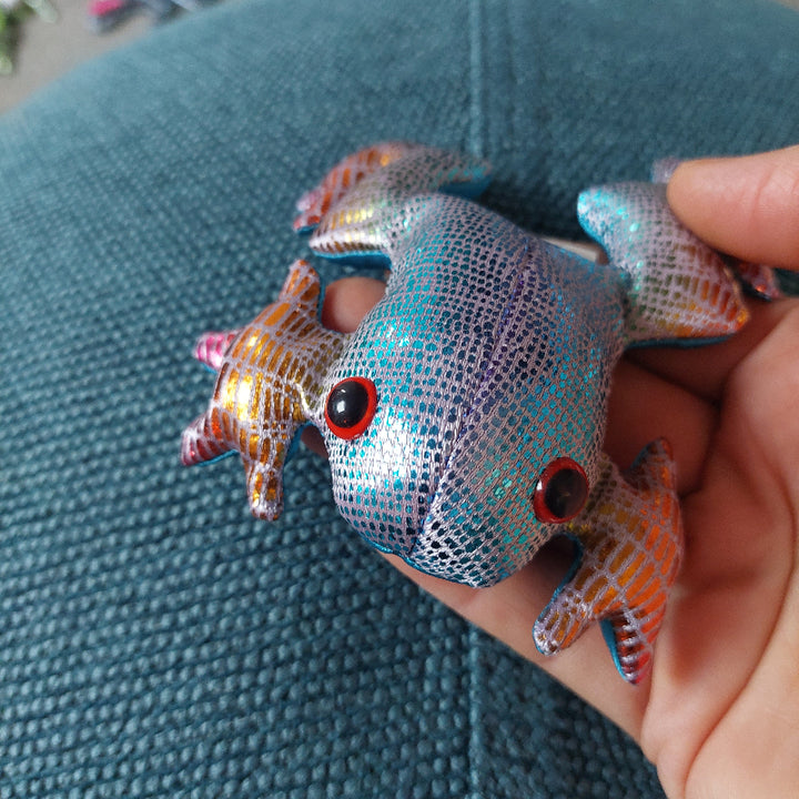 regenboog zanddier kikker op hand voor blauw achtergrond, lichtblauwe kikker met roze poten, goud op de poten, sensoriek materiaal