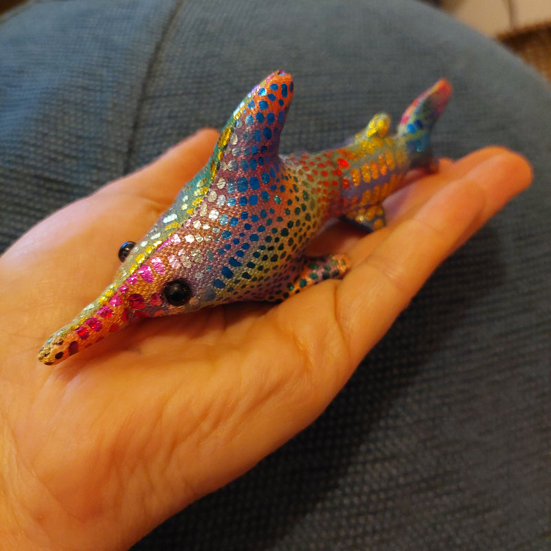 zanddier klein op hand, regenbogen kleur zanddier haai op blauwe achtergrond