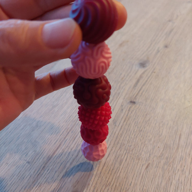 6 magnetische fidget ballen met structuur en van silicone, handen houden een bal, de anderen ballen hangen magnestisch eran vast