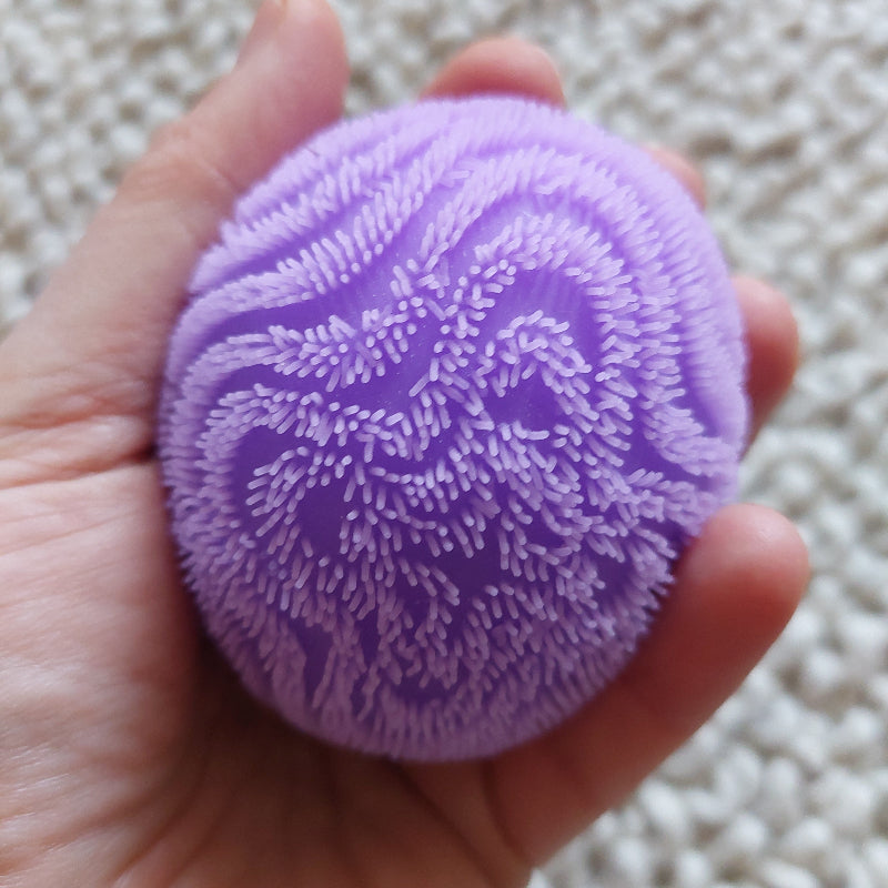 zachte needoh antistressball wave, fidget van needoh, paarse bal in hand, motoriekspeelgoed