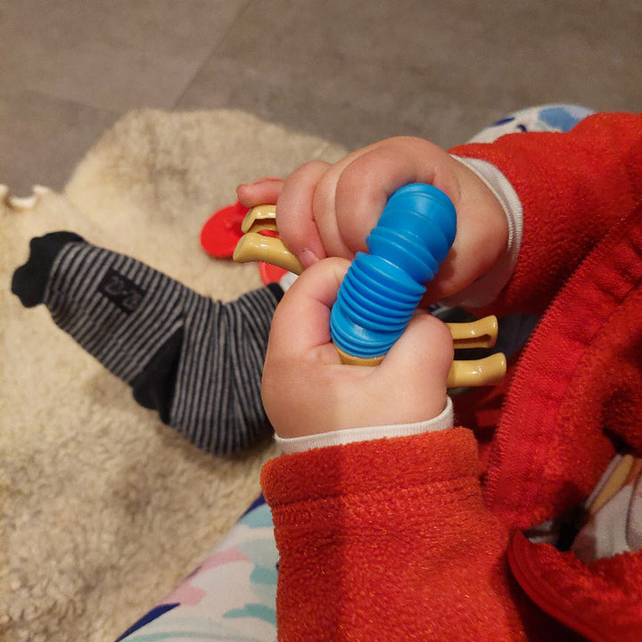 pop tube hond gebogen, kinderhanden aan het spelen, buig speelgoed, pop tube fidget