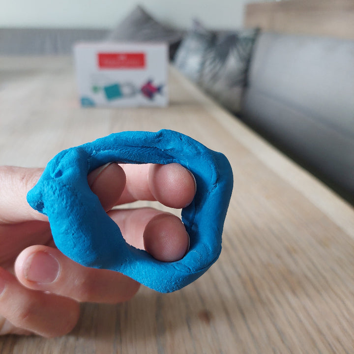 Kneedgum gebruikt als fingerkrachtoefening waarbij de vingers in een ring van klei stekken