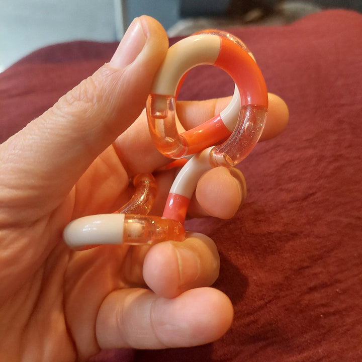 gedraaide tangle in hand op rode achtergrond, perziek tangle van tangecreation, peach