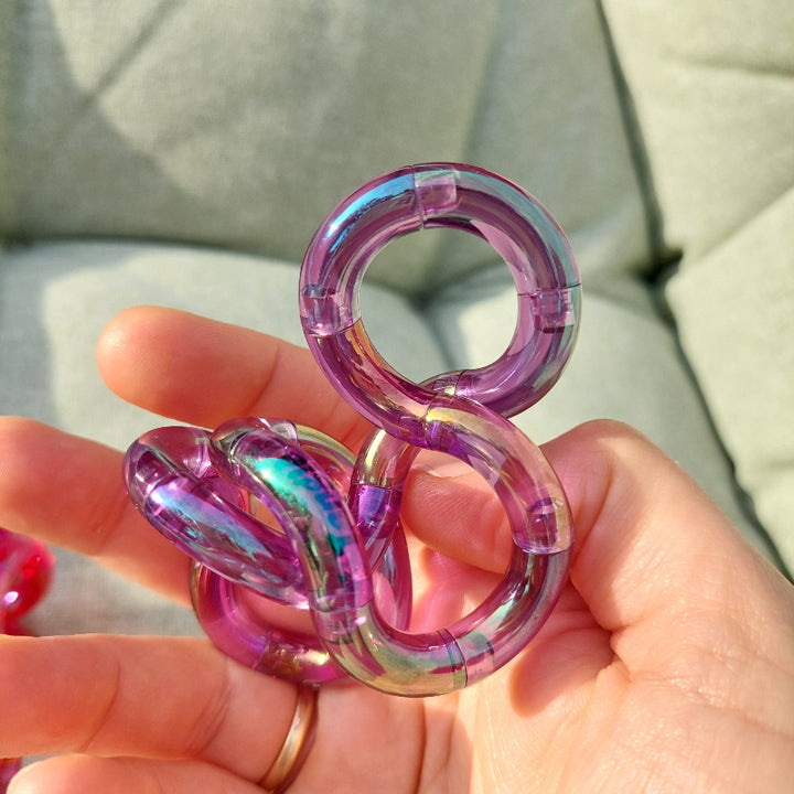 paarse gems tangle in hand, achtgrond tuinstoelkussen, de zon schijnt, de tangle licht op in verschillende kleuren.