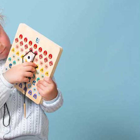 Kinderhanden rijgen volgens kleurcodes met Thread & Code, oefening voor focus en oog-handcoördinatie