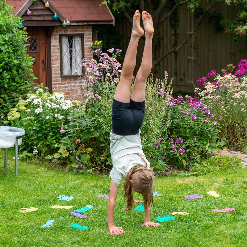 Kind maakt een handstand op kleurrijke sensorische hand- en voetvormen van siliconen