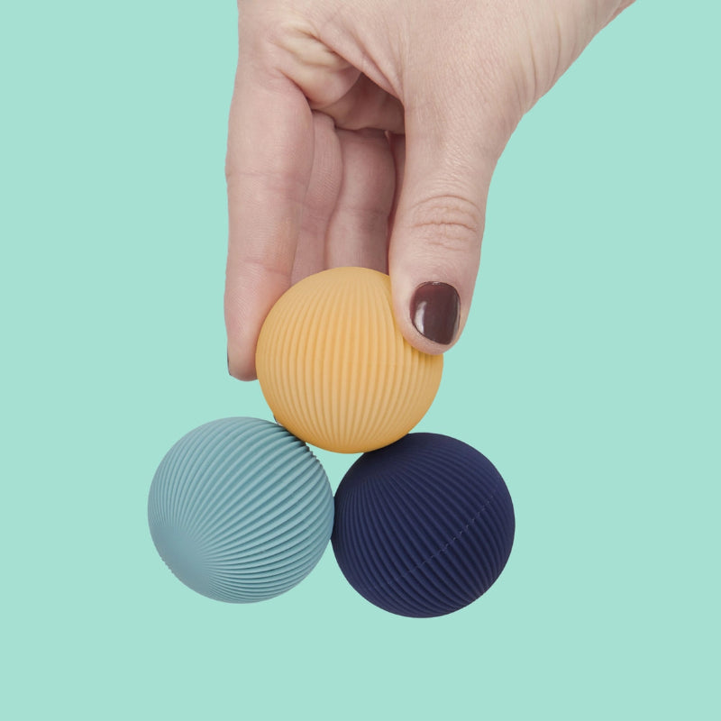 drie magneetballen in hand, volwassenen hand met nagellak houd massageballen met magneet, blauw en geel
