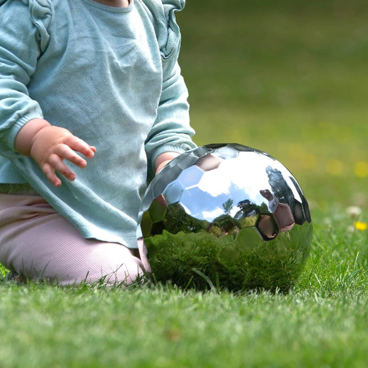 Kinderhanden rollen de sensorische spiegelbal over de grond , buitenspel, reflexie, sensoriek materiaal