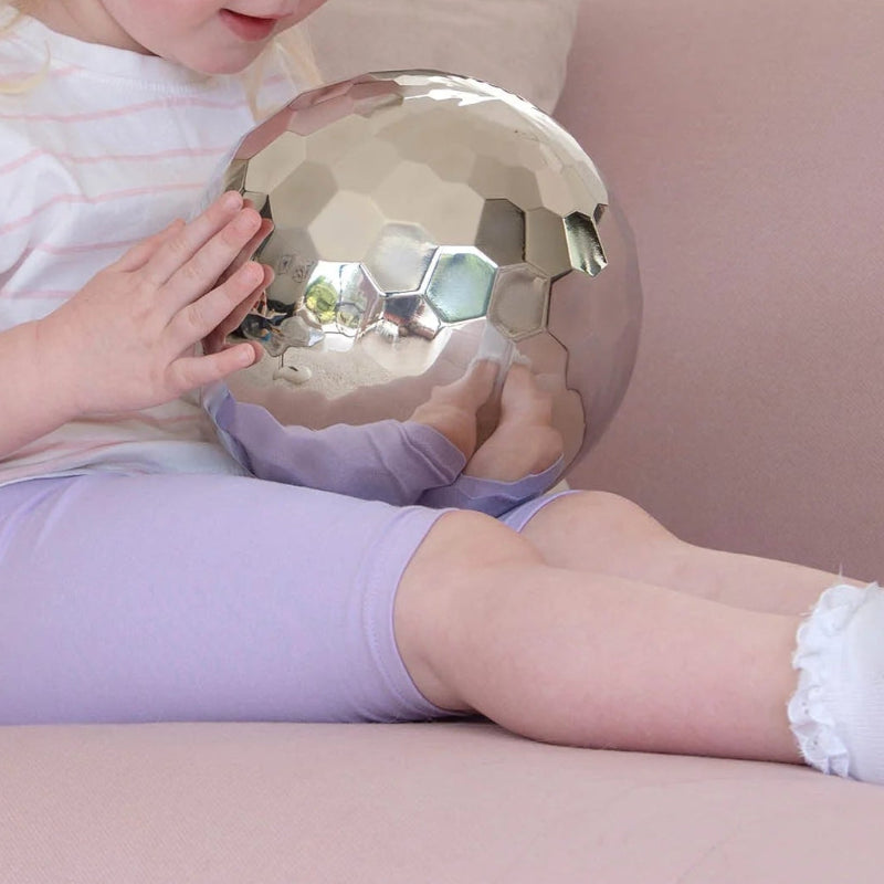 tickit sensorische stalen tuimelbal, kind met bal op schoot, si materiaal, sensoriek materiaal