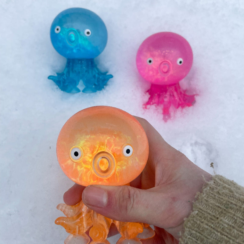 zuignap octupus oranje, roze en blauw in de sneeuw met hand