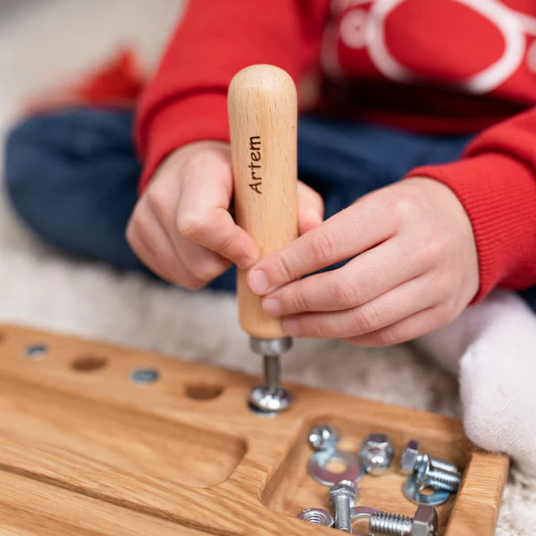 Kind oefent fijne motoriek en coördinatie door met een echte schroevendraaier een schroef in het houten screw board te draaien.