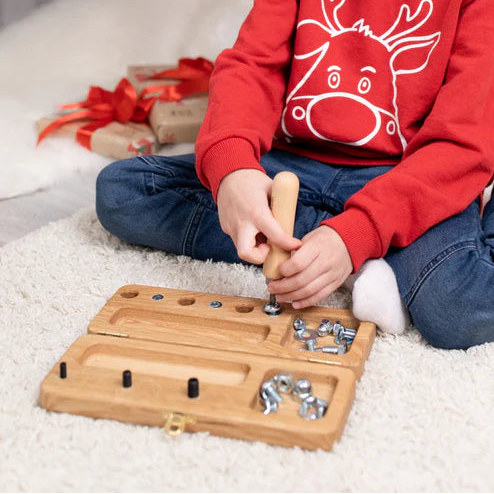 Kind verdiept zich in het draaien en vastzetten van schroeven op het houten oefenbord – versterkt aandacht, doorzettingsvermogen en motorische beheersing.