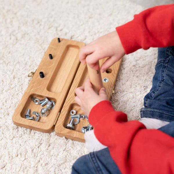 Tweehandige activiteit waarbij het kind het schroefbord stabiliseert en de andere hand draait – stimuleert samenwerking tussen beide handen.