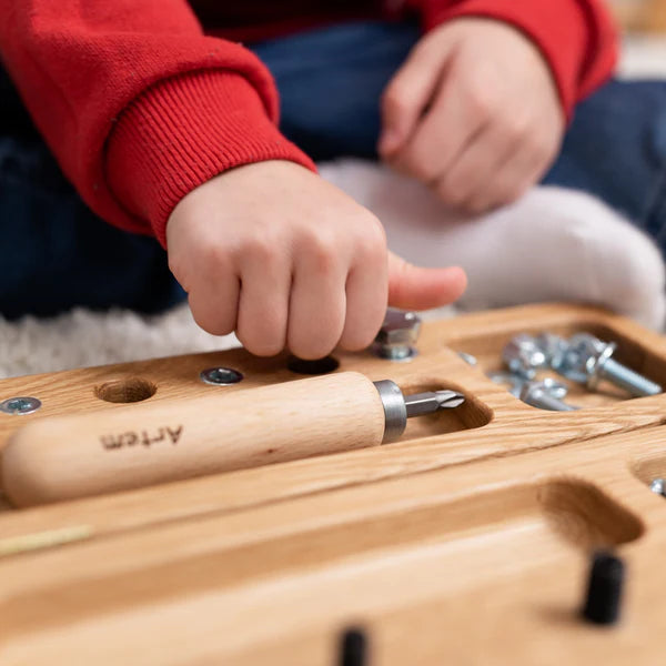 Kind sorteert verschillende bouten en moeren uit de houten box – oefening in waarneming, planning en concentratie.