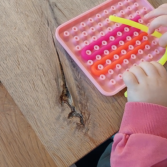 motoriekspel, silicone board met strecht snoertjes, kind aan het spelen, motoriekspel 