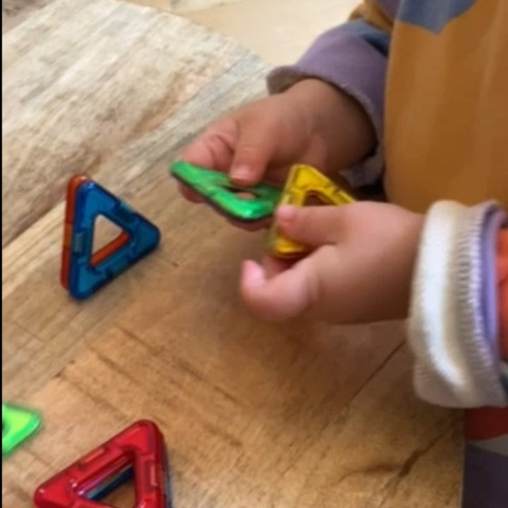kinderhnadjes spelen met magformer driehoekjes