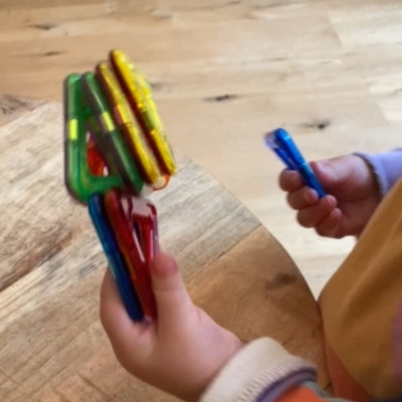 stapel magformer driehoekjes in een kinderhand, magneten, motoriekspeelgoed