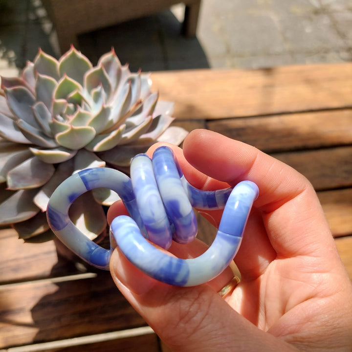 nieuwe tangle marble blauw, in hand, op houten tafel voor zomerplant, fidget speelgoed, friemel speelgoed, fidgettoys