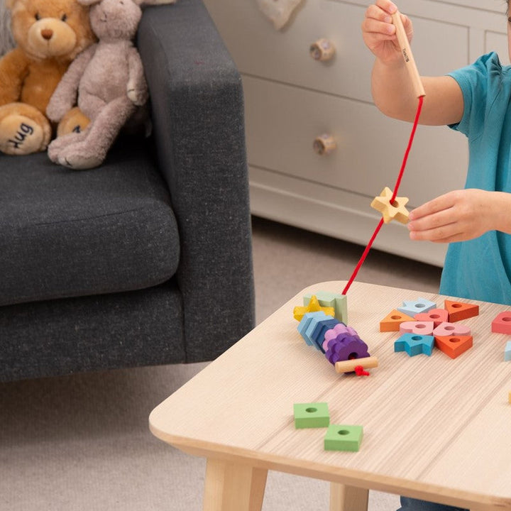 Spelend kind sorteert en rijgt houten regenboog vetervormen van Tickit