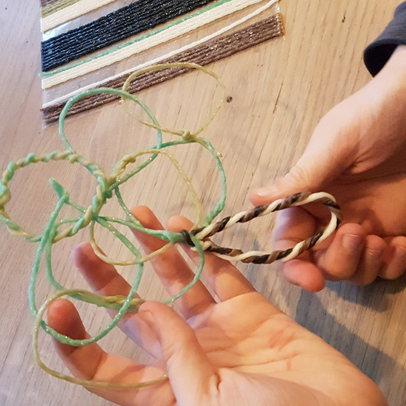 handen die Wikki Stix in natuurlijke kleuren buigen en vormen tot figuren