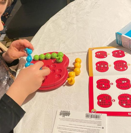 Kind speelt met SmartGames Apple Twist en buigt de rupsen op het appel spelbord