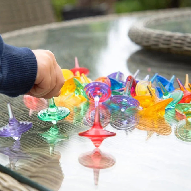 kinderhand met transparente tol op glasplaat tafel, motoriekspeelgoed